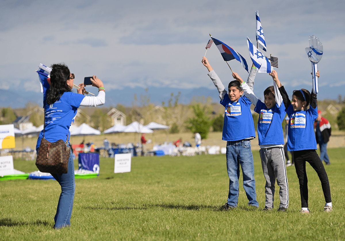 A mom takes a picture of her kids at Celebrate Israel @ 75